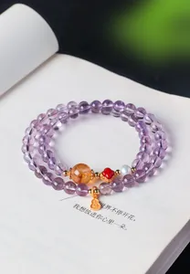 Détail du bracelet en améthyste naturelle avec pendentif gourde dorée et quartz rutilé.