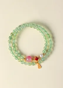 Vue détaillée d'un bracelet en perles de cristal vert avec un charme de gourde dorée.