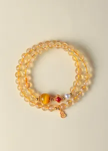 Détail d'un bracelet double rang en quartz rutilé doré avec pendentif gourde