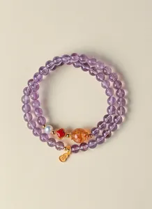 Vue détaillée d'un bracelet en améthyste naturelle avec breloques calebasse dorée.