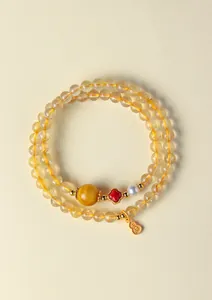 Détail d'un bracelet en quartz rutilé jaune naturel avec pendentif hulu doré