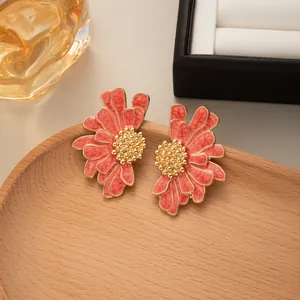 Dettaglio di orecchini a fiore color pesca in stile vintage con centro dorato su legno