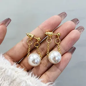 Primo piano di eleganti orecchini pendenti dorati con perle bianche.