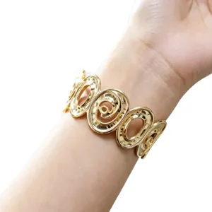 Elegante bracciale rigido largo dorato con design geometrico a spirale al polso