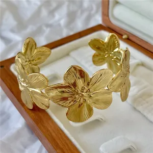 Elegante bracciale rigido a fiori dorati con petali testurizzati in una scatola per gioielli