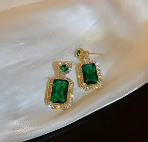 Vista dettagliata di orecchini a goccia con smeraldo rettangolare e alone lucente