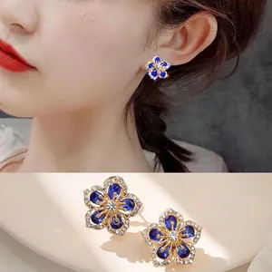 Detailansicht von blauen Zirkon-Blumenohrsteckern mit elegantem Goldfinish für Damen.