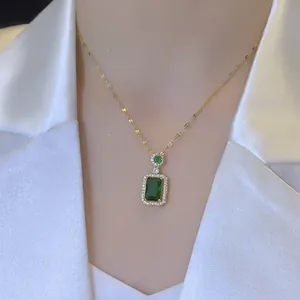 Dettaglio di una collana con pendente in cristallo verde smeraldo e catena d'oro sul collo