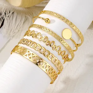 Primo piano dettagliato di un set di 6 braccialetti dorati con motivi geometrici e stelle.