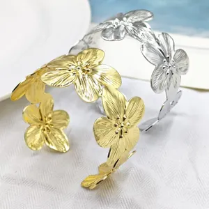 Vista macro dettagliata di due bracciali rigidi floreali regolabili in oro e argento
