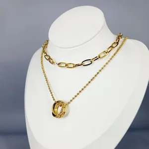 Dettaglio di una elegante collana a strati dorata con pendente ad anelli intrecciati