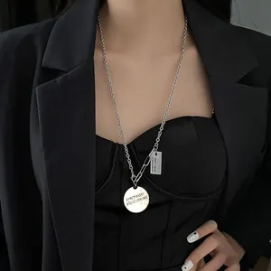Collana lunga trendy in argento con ciondoli a moneta e blazer nero stile streetwear
