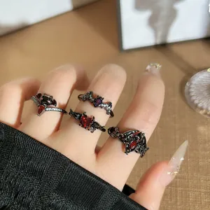 Gothic bat and demon wing open rings with red crystals on hand.