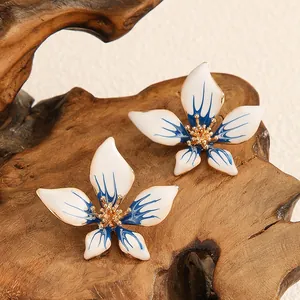 Dettaglio ravvicinato di eleganti orecchini a fiore a cinque petali sfumati blu e oro