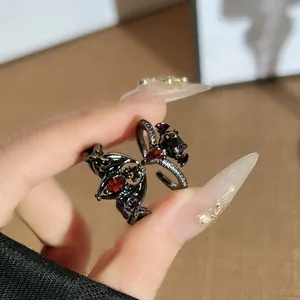 Close-up of gothic black bat demon wing open ring with red crystals.