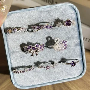 Détail de bagues en strass violets avec motifs cygne et nœud dans une boîte en velours