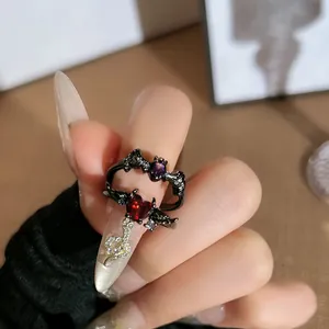 Macro detail of Gothic bat and demon wing open rings with red heart and purple stones