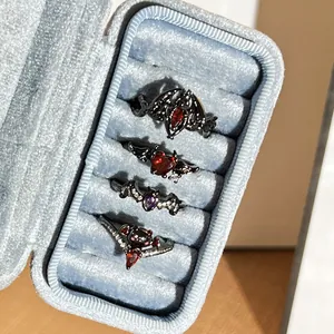 Set of four gothic black bat and devil wing open rings displayed in a blue velvet box