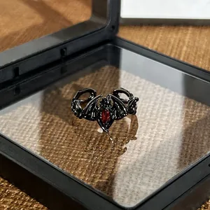 Macro detail view of a gothic black bat wing open ring featuring a red center gemstone
