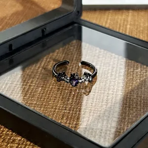 Close-up of gothic dark bat open ring with purple heart gemstone in a black gift box