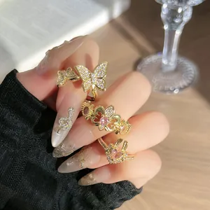 Primer plano de anillos de mariposa e iris dorados con diamantes rosa puestos en la mano