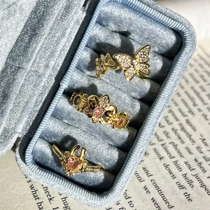 Primer plano de anillos vintage dorados con cristales rosas y blancos en caja azul