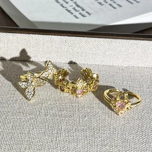 Primer plano de anillos dorados vintage con diseños de mariposas y corazones rosas