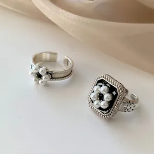 Détail de bagues en argent 925 avec fleur de perle et carré en émail noir