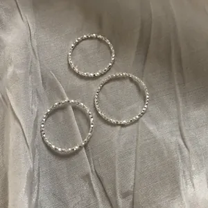 Primo piano di anelli scintillanti in argento sterling S925 su sfondo di seta elegante