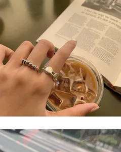 Detailed close-up of retro twisted woven silver rings worn on fingers in a cafe setting
