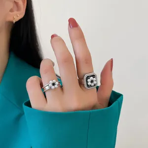 Gros plan de bagues en argent vintage avec des fleurs en perles.