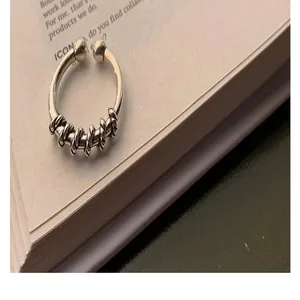 Close-up detail of vintage twisted woven silver open ring on minimalist aesthetic paper
