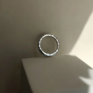 Nahaufnahme eines geometrischen s925 Silberrings mit Segmentdesign auf einem weißen Podest