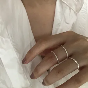Dettaglio ravvicinato di tre sottili anelli in argento sterling s925 indossati sulla mano.