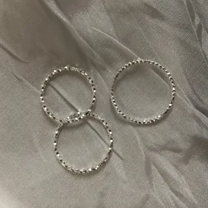 Dettaglio macro di tre anelli scintillanti in argento sterling S925 sfaccettato su seta