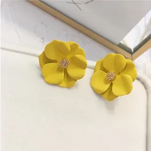 Eleganti orecchini a fiore giallo opaco con centro in cristallo su vassoio bianco