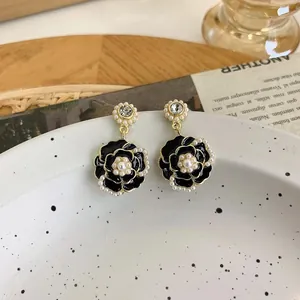Primo piano di eleganti orecchini camelia nera con dettagli in perle e cristalli.