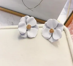 Dettaglio macro di eleganti orecchini a lobo a fiore bianco con finitura opaca e centro dorato