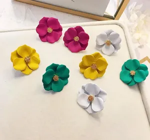 Orecchini a fiore opaco in vari colori vivaci su un vassoio espositivo bianco.