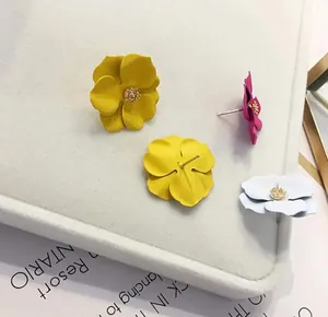 Dettaglio di orecchini a lobo a forma di fiore colorati con perle su vassoio grigio