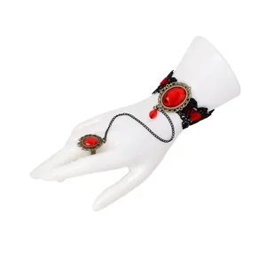Dettaglio bracciale gotico in pizzo nero con gemma rossa e anello dorato vintage