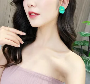 Primo piano di eleganti orecchini a lobo a fiore verde menta indossati da una modella nel verde