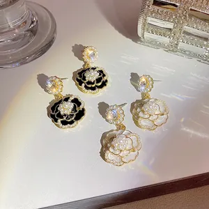 Dettaglio di eleganti orecchini a forma di camelia neri e bianchi con perle.