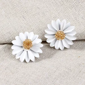 Detailed macro view of white daisy flower earrings featuring a textured gold center core