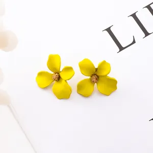 Dettaglio di orecchini a lobo a forma di fiore giallo con centro dorato glitter