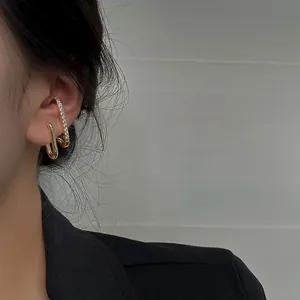 Close-up detail of elegant gold-toned earrings with crystals worn by an Asian model