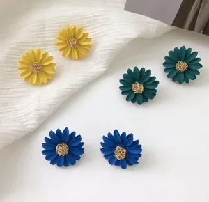 Detailed view of colorful daisy flower stud earrings in yellow, green and blue