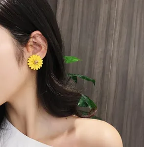 Close-up detail of a vibrant yellow daisy flower earring worn by a model in Korean style