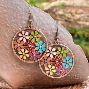 Dettaglio di orecchini bohémien in bronzo con motivi floreali in smalto colorato