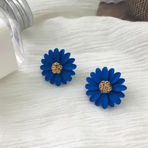 Elegant vibrant blue daisy stud earrings with textured gold center on white fabric